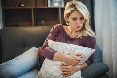 Evdeki kanepede yatarken depresif ve üzgün görünen çekici bir genç kadının fotoğrafı..