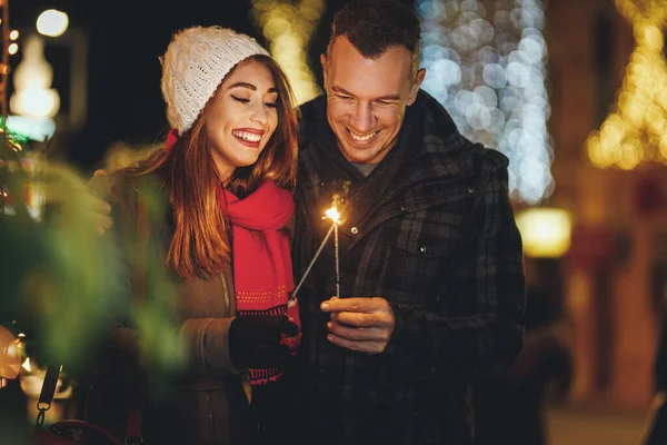 Havai Fişekli Gülümseyen Bir Çiftin Çekimleri Noel Arifesinde Şehrin Işıklarıyla — Stok fotoğraf