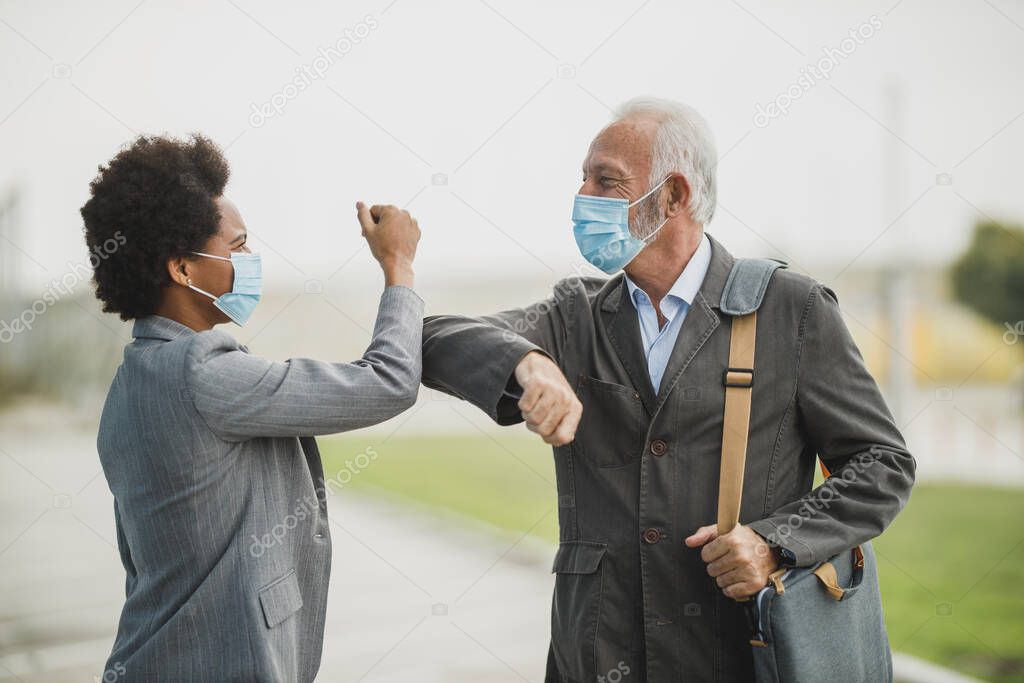 Shot of a multi-ethnic business people greeting with bumping elbows outdoors during COVID-19 pandemic to avoid handshakes.