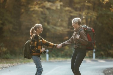 Genç bir kız ve annesinin sonbaharda ormanda birlikte yürürken çekilmiş fotoğrafı..