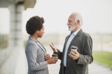 Ofis binasının önünde kahve molası verirken iki başarılı çoklu etnik iş adamının görüntüsü..