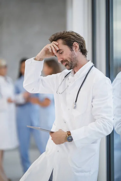 Medico Cerca Esaurimento Mentre Piedi Vicino Una Finestra Utilizzando Tablet — Foto Stock