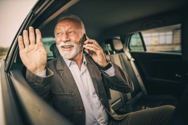 通勤中に車の後部座席に座っている間に スマートフォンで話して手を振って成功した先輩のショット — ストック写真