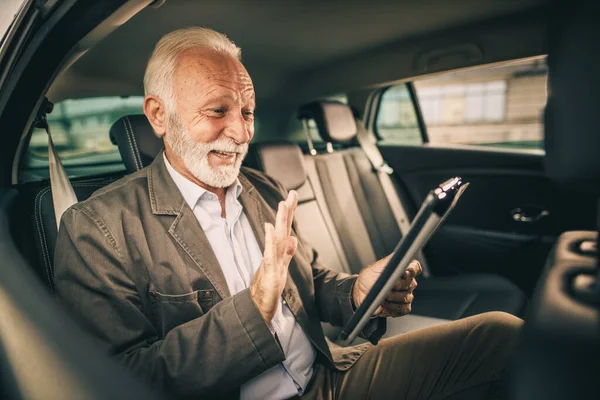 彼のビジネス通勤中に車の後部座席に座っている間 デジタルタブレット上でビデオ通話を持つ成功した高齢者のショット — ストック写真