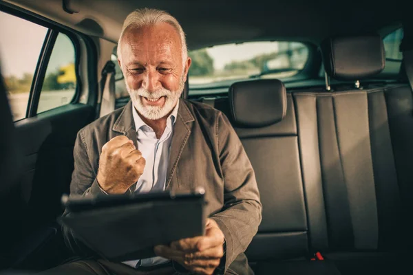 彼の朝の通勤中に車の後部座席に座っている間 デジタルタブレットを使用して成功した高齢者のビジネスマンのショット — ストック写真