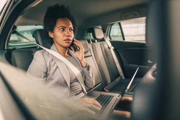 通勤中に車の後部座席に座っている間にスマートフォンで話している心配そうな黒人ビジネスマンのショット — ストック写真