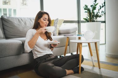 Çekici genç bir kadın öğleden sonra evinde çay içmekten zevk alır..