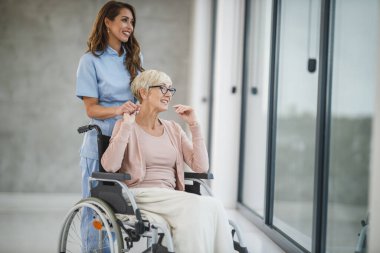 Genç bir kadın hemşirenin tekerlekli sandalyeye mahkum yaşlı bir kadını umursaması..