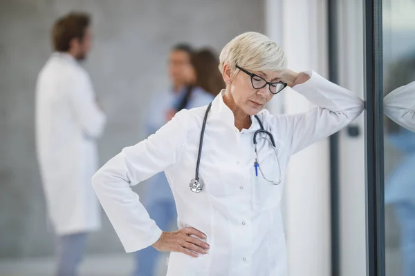 Shot Tired Senior Doctor Relaxing While Standing Window Hospital Hallway — Stock Photo, Image