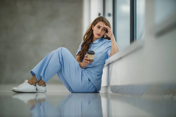 Una Joven Enfermera Preocupada Sentada Suelo Cerca Una Ventana Mientras —  Fotos de Stock