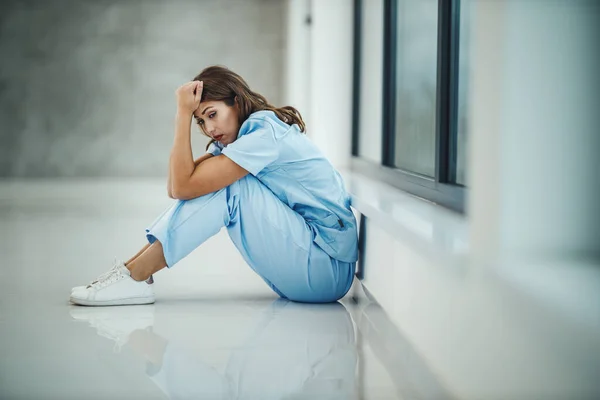 Una Joven Enfermera Estresada Sentada Suelo Cerca Una Ventana Mientras —  Fotos de Stock