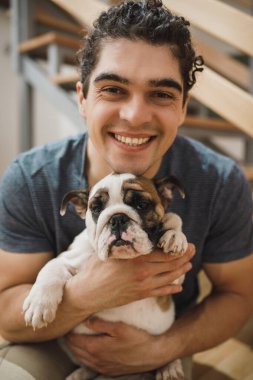 Yeni evlerine taşınırken İngiliz bulldog köpeğiyle mutlu bir gencin portresi. Kameraya bakıyorum..