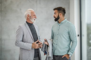 Modern bir ofiste yürüyen ve konuşan kendine güvenen iki iş adamı..