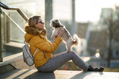 Çekici bir kadın köpeğini açık havada tutuyor..