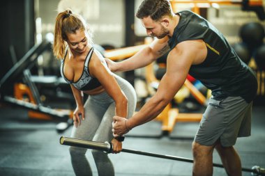 Çekici bir genç kadının spor salonunda kişisel antrenörle çalışması..