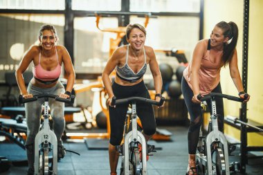 Spor salonunda spor bisikleti eğitimi alan üç formda bayan arkadaş grubu..