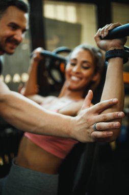 Çapraz antrenman salonunda kişisel antrenörle çalışan çekici bir genç kadın..