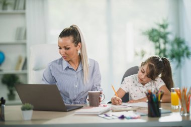 Tatlı kızı evde öğrenirken bekar anne dizüstü bilgisayar kullanıyor..