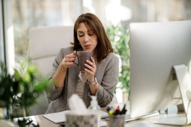 Çekici bir iş kadını ofiste kahve içiyor..