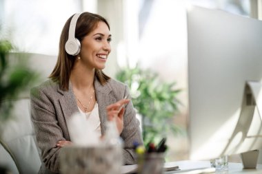 Çekici bir iş kadını evinde kulaklıklarıyla yalnız oturuyor ve bilgisayar başında çalışıyor..