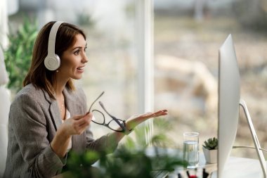 Ev bilgisayarında çalışan kulaklıklı çekici bir genç kadın..