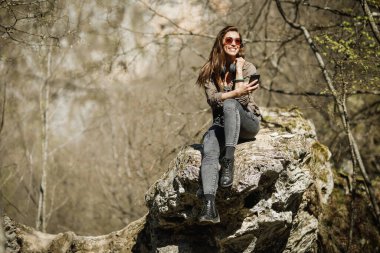 Kaygısız genç bir kadın dağın tepesinde oturuyor ve dışarıda eğleniyor..
