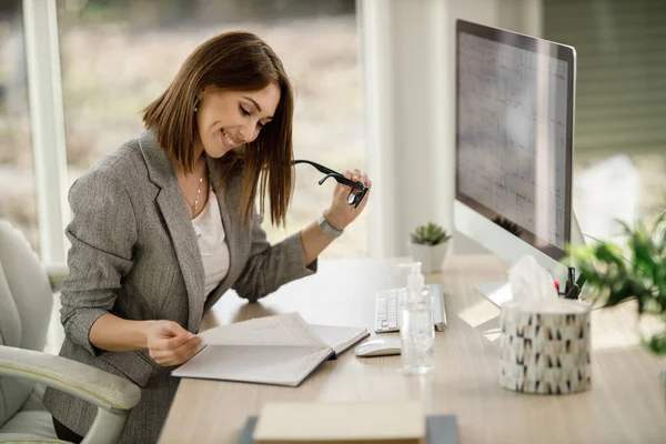 Una Atractiva Mujer Negocios Sonriente Revisando Algo Cuaderno Mientras Trabaja — Foto de Stock