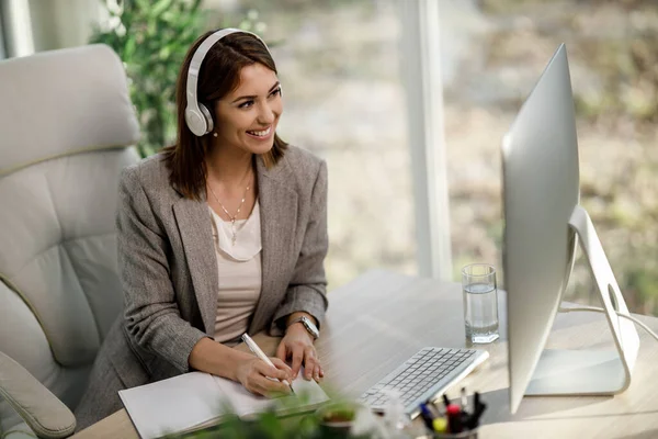 Uśmiechnięta Bizneswoman Słuchawkami Pomocą Komputera Aby Mieć Konferencję Internetową Biurze — Zdjęcie stockowe
