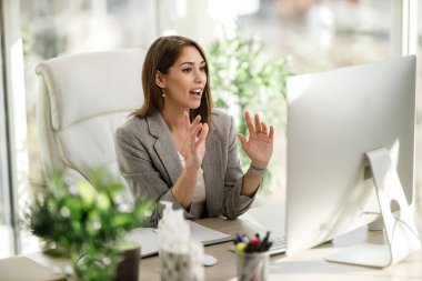 İnternette konferans yapmak için bilgisayar kullanan çekici bir genç kadın..