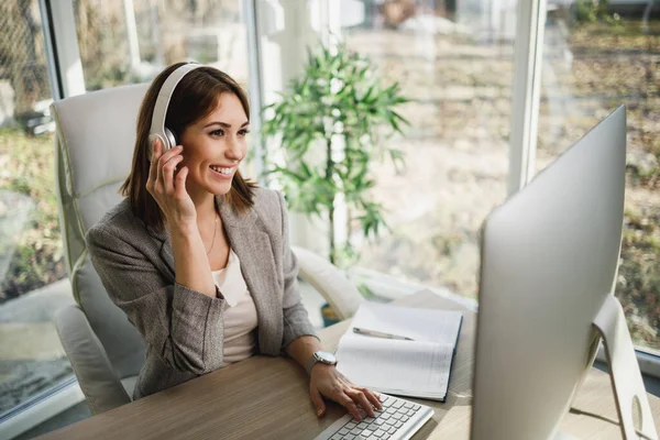 Una Mujer Negocios Sonriente Sentada Sola Oficina Casa Con Auriculares —  Fotos de Stock