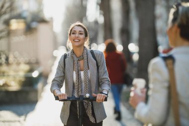 Genç bir iş kadını elektrikli scooterla işe gidiyor..