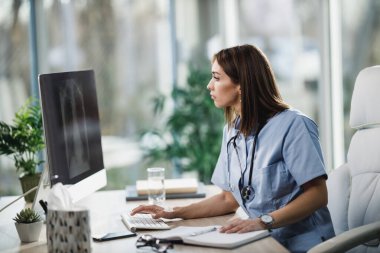 Hastanede bilgisayardaki röntgenleri analiz eden çekici genç bir hemşire..