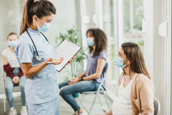 Verpleegster Praat Met Jonge Zwangere Vrouw Voor Covid Vaccin Wachtkamer — Stockfoto