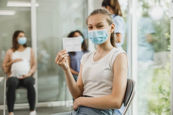 Een Lachend Tienermeisje Met Een Glimlach Die Een Vaccinatiebewijs Toont — Stockfoto