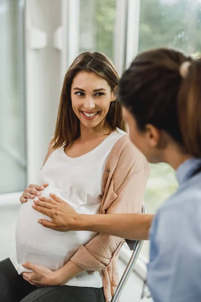 魅力的な妊娠中の女性は看護師と話しながら 婦人科医のチェックを待ちます — ストック写真