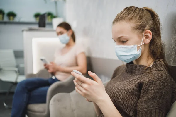 Een Schattig Tienermeisje Draagt Gezichtsmasker Gebruikt Haar Mobiele Telefoon Wachtkamer — Stockfoto