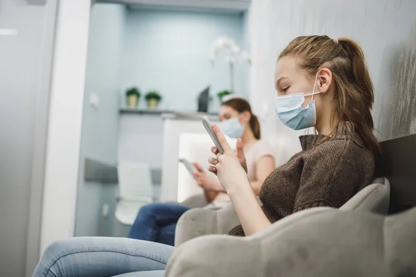 Een Schattig Tienermeisje Draagt Gezichtsmasker Gebruikt Haar Mobiele Telefoon Wachtkamer — Stockfoto