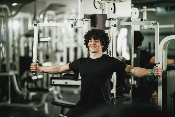 Joven Musculoso Está Entrenando Máquina Gimnasio —  Fotos de Stock