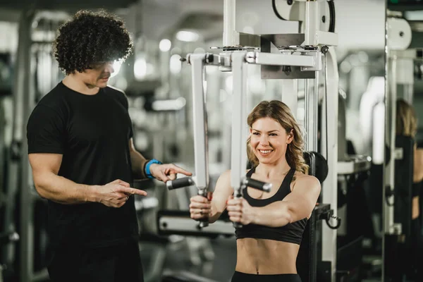 Uma Jovem Mulher Musculosa Está Fazendo Treinamento Máquina Apoio Pelo — Fotografia de Stock