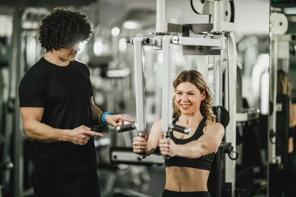 Una Joven Musculosa Está Haciendo Entrenamiento Máquina Apoyo Por Entrenador — Foto de Stock