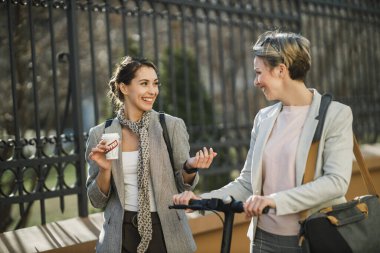 İki başarılı iş kadını şehirde yürürken kısa bir ara verip sohbet ediyorlar..