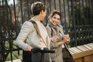 İki başarılı iş kadını şehirde kahve molası verirken sohbet ediyorlar..