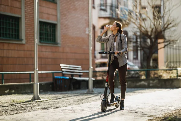 一位年轻的女商人在上班的时候用电动车喝咖啡 — 图库照片
