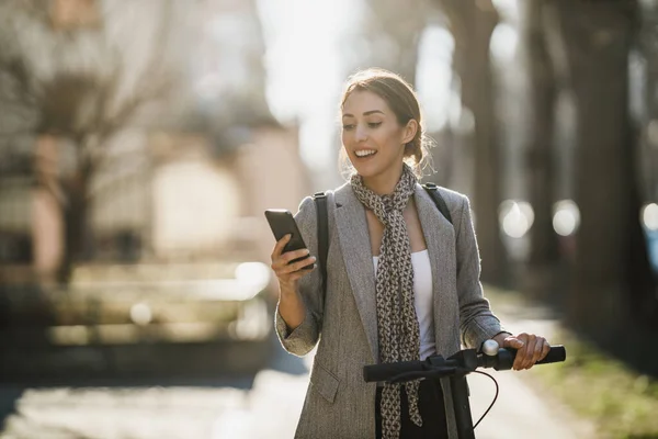 Ung Affärskvinna Rider Elektrisk Skoter Och Använder Smartphone Väg Till — Stockfoto