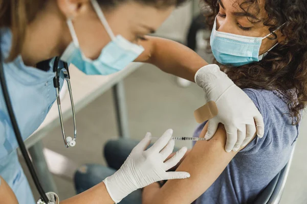 一名护士因患大肠癌而向非洲裔美国少女注射疫苗的特写镜头 — 图库照片