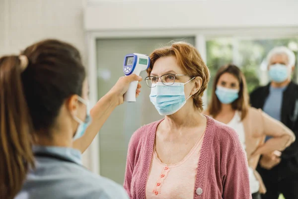 Verpleegster Meten Temperatuur Van Een Oudere Vrouw Tijdens Het Wachten — Stockfoto