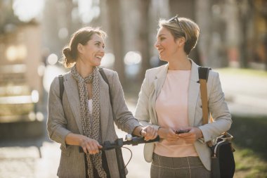 İki başarılı iş kadını şehirde yürürken sohbet ediyorlar..