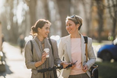 İki başarılı iş kadını şehirde yürürken kısa bir ara verip sohbet ediyorlar..