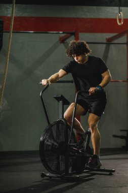 Genç kaslı bir adam spor salonunda motorlu taşıt eğitimi alıyor..