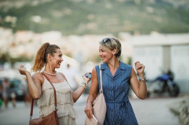 İki mutlu genç kadın yaz gününde eğleniyor ve eğleniyorlar. Bir Akdeniz kasabasının caddesinde yürürken..